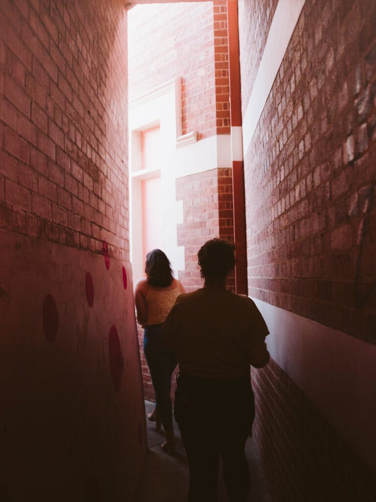 two people in dark brick walled alleyway