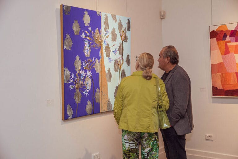 a man and woman looking at a purple and white painting