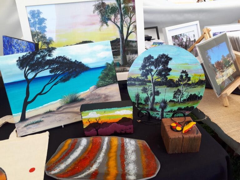 collection of bush scene paintings and art displayed on a table