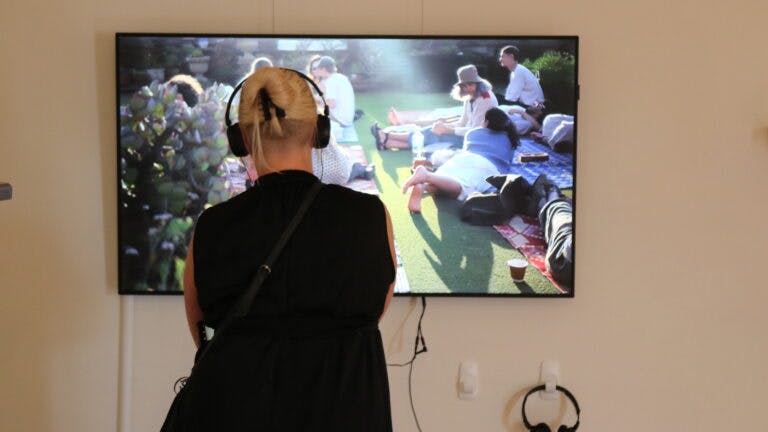 Person wearing headphones with back to camera looking at TV screen